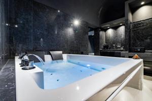 a large bath tub in a bathroom with black tiles at 4 Suites " unconventional living rooms " in Catania