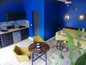 een woonkamer met blauwe muren en gele stoelen en een tafel bij Gite rural cocooning en Baie de Somme in Vron