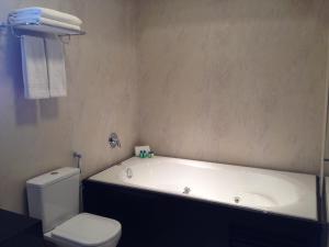 a bathroom with a white tub and a toilet at Denali Hotel in Anápolis