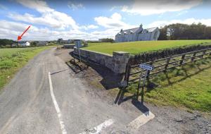 a road with a fence and a house in the background at Enniscrone Apartment in Enniscrone