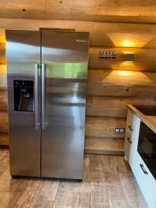 a stainless steel refrigerator in a kitchen with wooden walls at Waldstein Chalet in Zell im Fichtelgebirge +7 photos