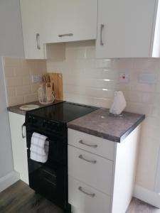 a kitchen with a black stove and white cabinets at Atlantic way Apartment 1 in Breaghwy