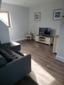 a living room with a couch and a flat screen tv at Atlantic way Apartment 1 in Breaghwy