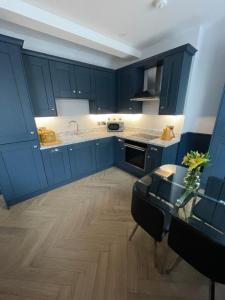 cocina con armarios azules y mesa de cristal en Roe Valley Apartments, en Limavady