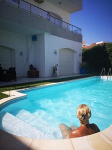 une femme qui se couche dans une piscine à côté d'une maison dans l'établissement Residence les Jasmins, à Sousse