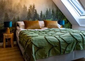 a bedroom with a bed with a forest mural on the wall at TATANKA Dom w Puszczy in Białowieża