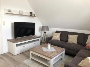 uma sala de estar com um sofá e uma televisão de ecrã plano em Greetje Oog em Krummhörn