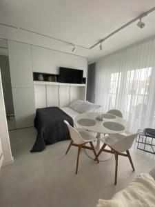 Un dormitorio con una cama y una mesa y sillas. en WhiteWave Apartament Pogorzelica, en Pogorzelica