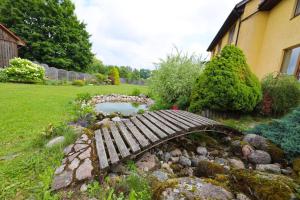 a wooden bridge over a pond in a garden at Greenland Apartments in Cēsis