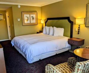 ein Hotelzimmer mit einem großen Bett und einem Stuhl in der Unterkunft The Bard's Inn - BW Signature Collection by Best Western in Ashland