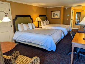 ein Hotelzimmer mit 2 Betten und einem Tisch in der Unterkunft The Bard's Inn - BW Signature Collection by Best Western in Ashland