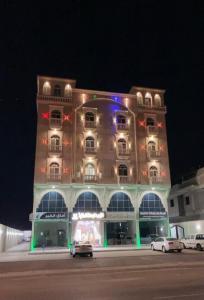 un grand bâtiment avec des voitures garées devant lui dans l'établissement الزمرد للشقق المخدومة, à Khobar