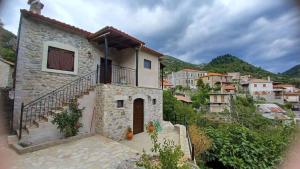 a stone house with a balcony on a mountain at Rodanthe's Guest House in Stemnitsa