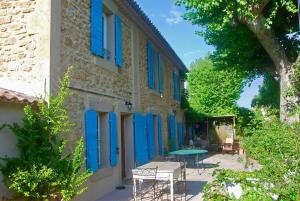 un edificio con porte blu e tavolo e sedie di Les Volets Bleus Provence a Salon-de-Provence
