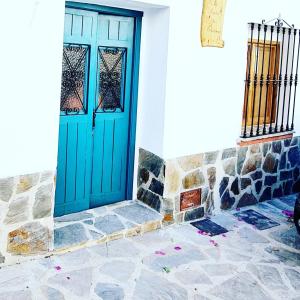 - une porte bleue dans un bâtiment blanc avec du carrelage dans l'établissement Preciosa casa de pueblo entre Ronda y Setenil La Posada de Catalina, à Montecorto