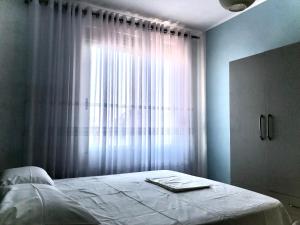 een slaapkamer met een bed en een raam met gordijnen bij Sea View Apartment Shkëmbi i Kavajes in Durrës
