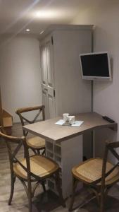 een kamer met een tafel en stoelen en een televisie bij Beau studio au calme proche de la cathédrale in Autun