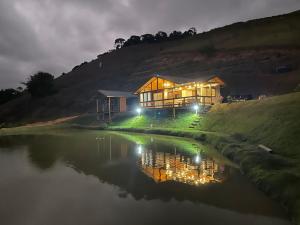 a house on the side of a river at night at Rancho Nosso Lago in Domingos Martins