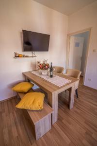 een eetkamer met een tafel en gele kussens bij Apartmani Tonkica in Supetarska Draga