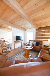 a living room with leather furniture and a wooden ceiling at La Maison Bleue in Saint-Férréol-les-Neiges