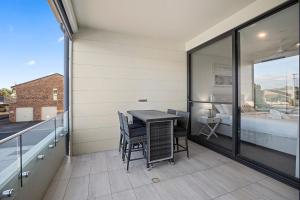 a balcony with a table and chairs and a bedroom at Rockpool 2 Sawtell in Sawtell