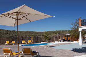 eine Terrasse mit Stühlen, einem Sonnenschirm und einem Pool in der Unterkunft Casa de las Montañas in Villanueva del Trabuco