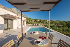 a patio with a table and chairs and a swimming pool at Ionian Sunshine Villas in Paleros