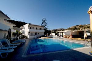 a swimming pool with lounge chairs next to a building at Villa Popi Studios in Kefalos