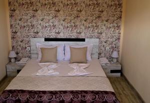a bedroom with a large bed with two tables at Къща за гости Ваканция in Ezerets