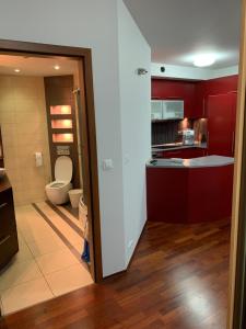 a bathroom with a toilet and a kitchen with red cabinets at Krowoderska Apartment in Krakow