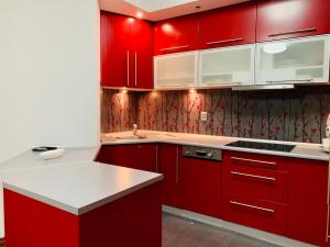 a red kitchen with white counters and red cabinets at Krowoderska Apartment in Krakow