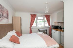 ein Schlafzimmer mit einem großen weißen Bett mit orangefarbenen Kissen in der Unterkunft Modern Apartments in Bromley, Greater London near Tesco and Sundridge Park Station in Bromley