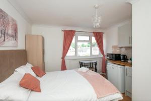 a bedroom with a large white bed with orange pillows at Modern Apartments in Bromley, Greater London near Tesco and Sundridge Park Station in Bromley