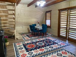 a dining room with a table and chairs on a rug at Satul de Vacanța Carla in Stremţ