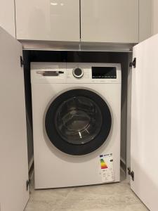 a white washing machine is in a cabinet at Beach front apartment in Bogazici