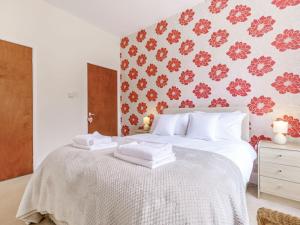 スカーバラにあるTree Topsの赤い花の壁紙を用いた白いベッド1台が備わるベッドルーム1室