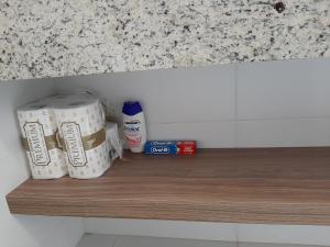 3 rollos de papel higiénico sobre una estantería de madera en Flat pensado para sua tranquilidade e alegria en Campos dos Goytacazes