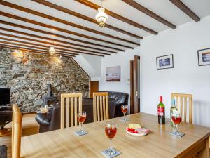 a dining room with a wooden table with wine glasses at Pen Y Bont in Aberdaron