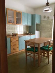 a kitchen with blue cabinets and a wooden table and chairs at Casa sul lago Nonna Gio' in Colle di Tora