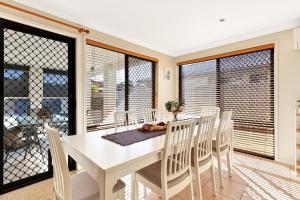 a dining room with a white table and chairs at Pet Friendly 5 BR Family Home w Pool at Caloundra in Caloundra West