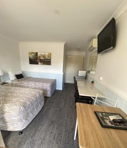 a hotel room with two beds and a desk at Centrepoint Midcity Motor Inn in Warwick