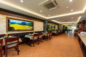 a restaurant with tables and chairs and a painting on the wall at Liberty Hall Tam Coc Hotel & Villa in Ninh Binh