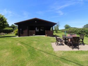 a cabin with a table and chairs in the grass at Cedar Lodge in Bodmin