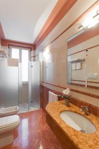 ein Badezimmer mit einem Waschbecken, einem WC und einem Spiegel in der Unterkunft Hotel Gambara in Gambara