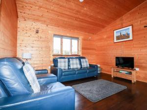 a living room with leather couches and a television at Maple Lodge in Bodmin