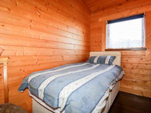 a bedroom with a bed in a wooden cabin at Maple Lodge in Bodmin