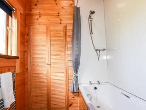 a bathroom with a tub and a wooden door at Maple Lodge in Bodmin +8 photos