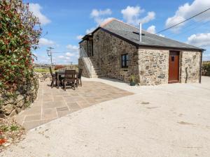 ein Cottage aus Stein mit einem Tisch und Stühlen davor in der Unterkunft Sunnywell in Bodmin