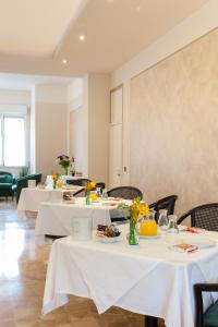 un restaurante con mesas blancas y sillas con flores. en Hotel Gambara en Gambara