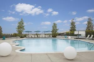 ein großer Pool mit Stühlen und Sonnenschirmen in der Unterkunft Hyatt Regency Los Angeles International Airport in Los Angeles